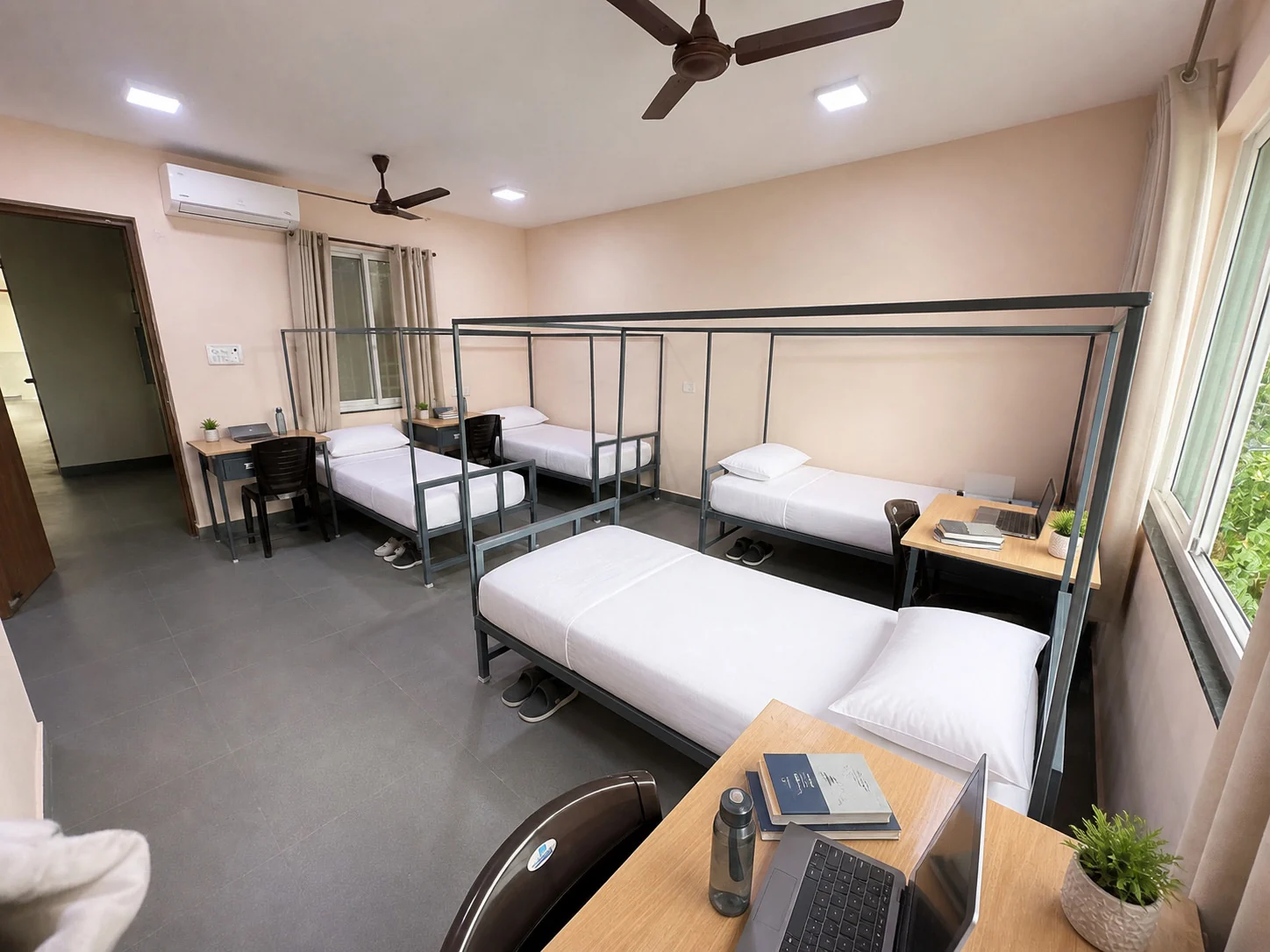 Bright quad sharing room with four beds and workspaces